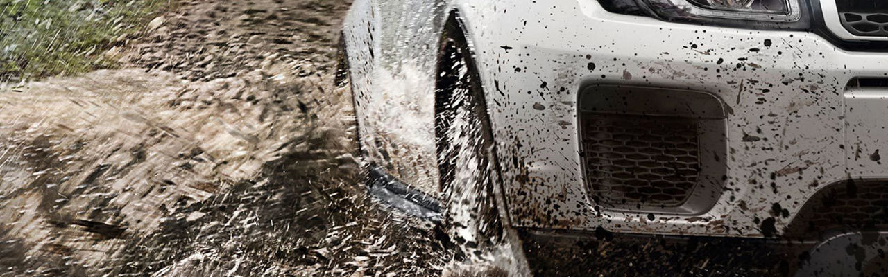 Close up of Land Rover driving through water and mud