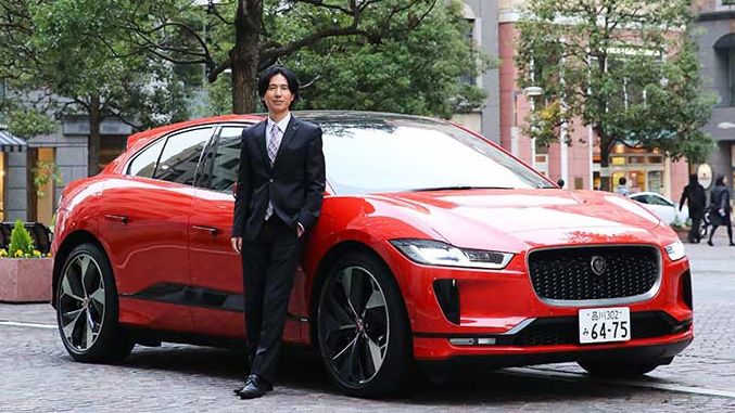 Man with suite in-front of red JAGUAR