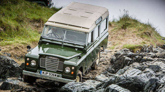 Classic Land Rover Defender driving down rocky hillside