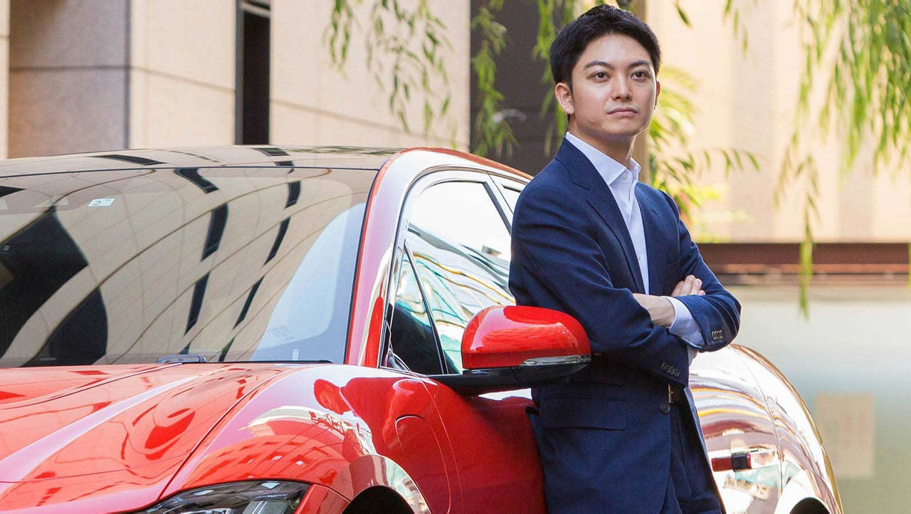 A man standing beside red Jaguar car