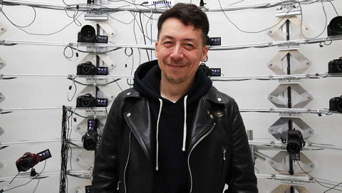 A man smiling and standing before multiple cameras