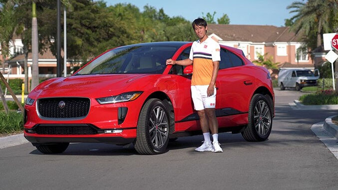 Man in yellow shirt posing in-front Red JAGUAR