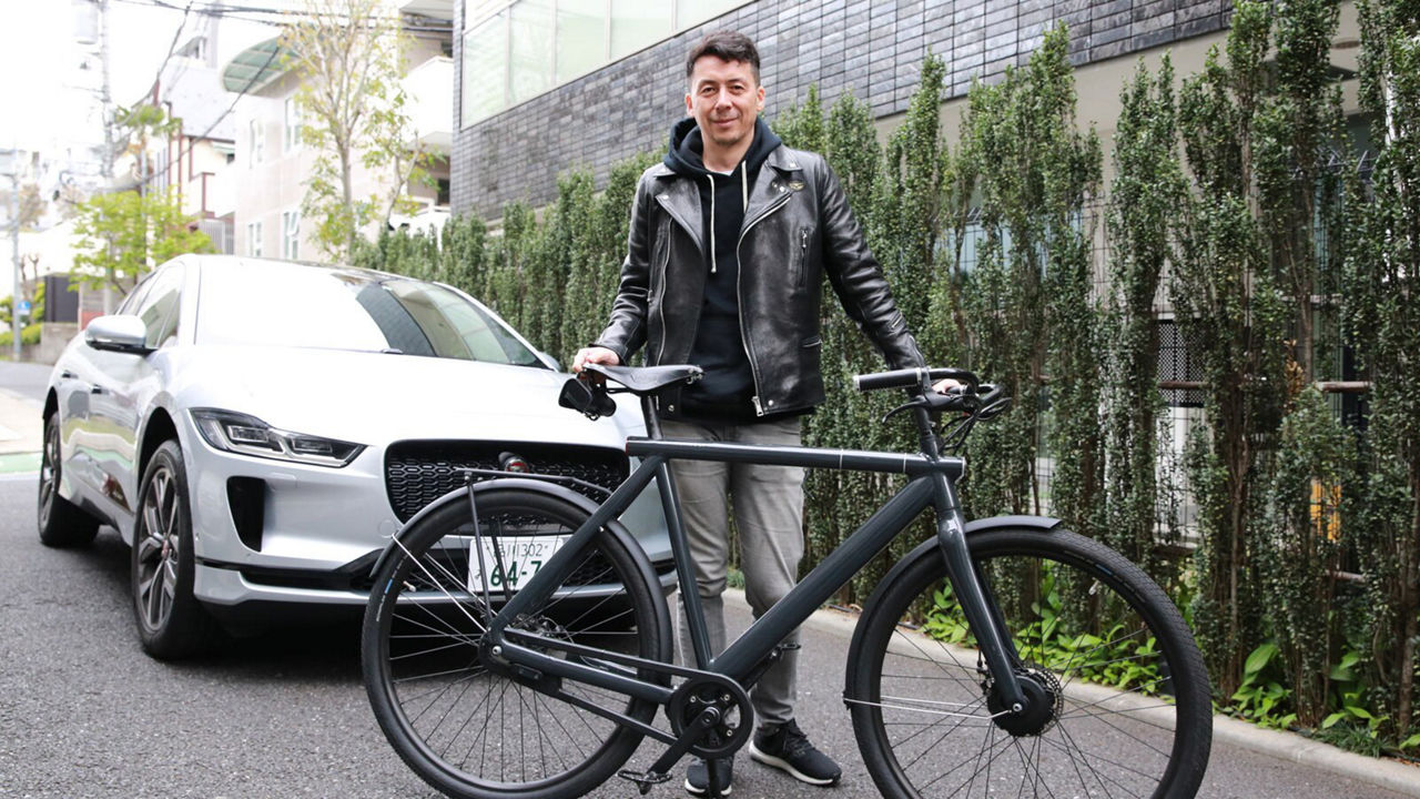 Naoko Tanijiri with a bicycle in front of a Jaguar I-Pace