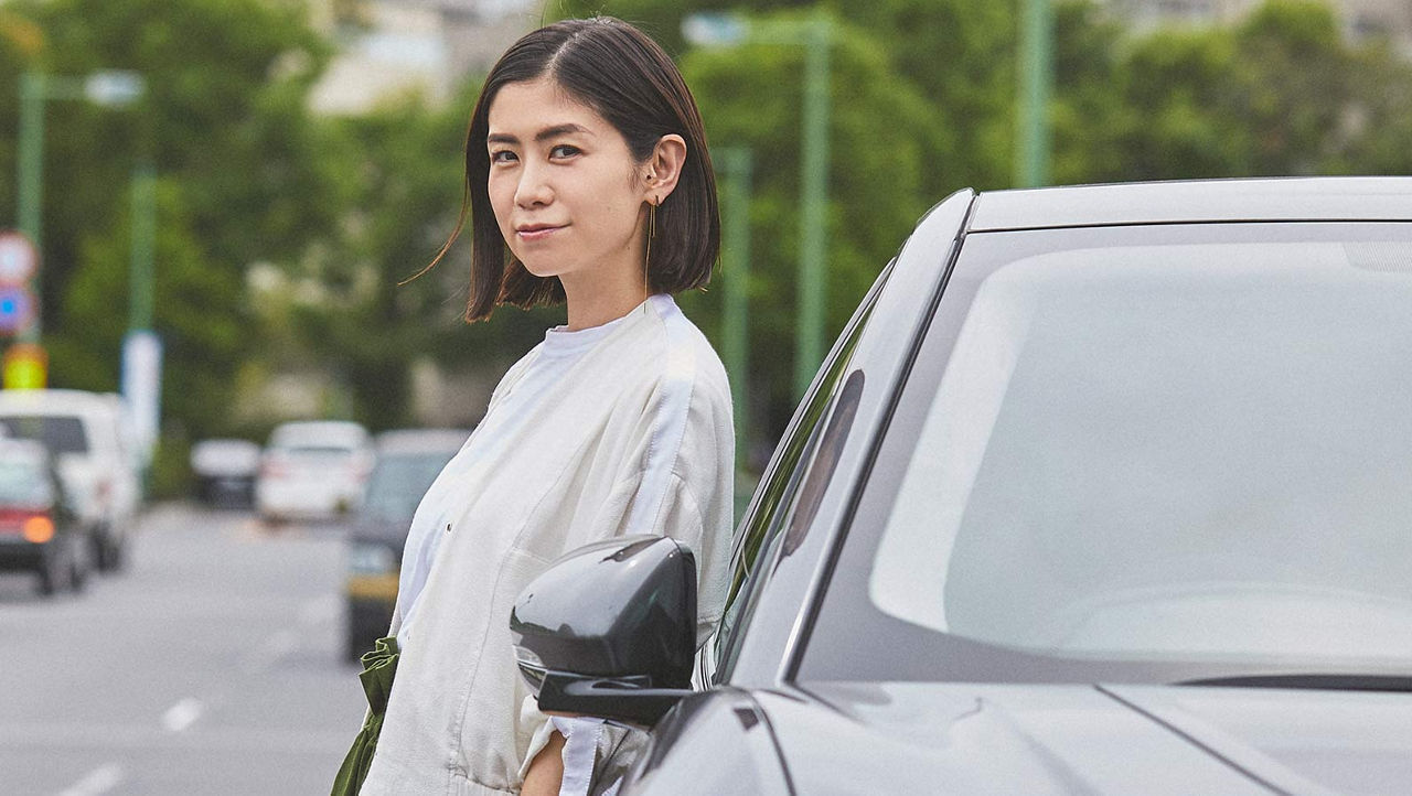 A girl standing beside a car in a city environment