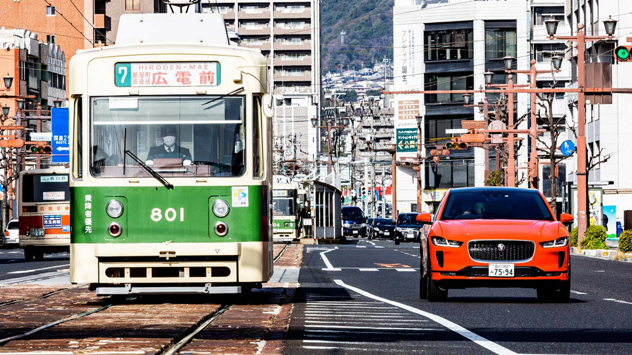 Orange JAGUAR on road with Tram