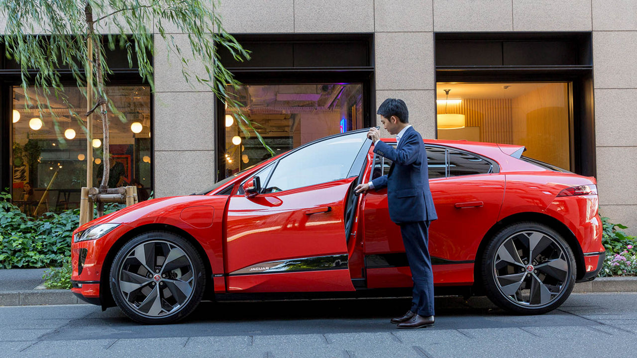 Retsu Kitagawa next to a red I-Pace