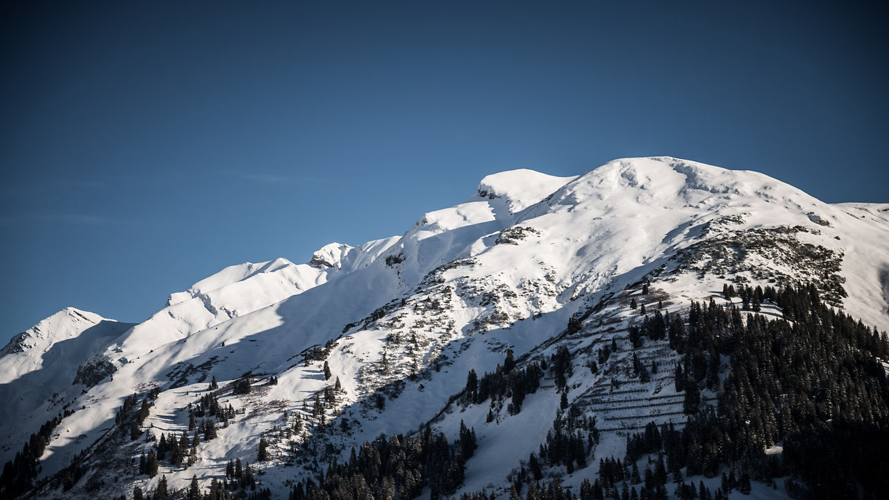  A view of a snow-covered mountain set beneath a blue sky on a winters day.