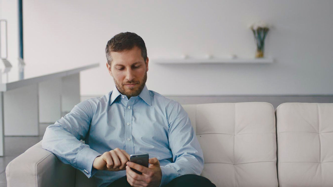 A Man seating on couch and surfing on mobile