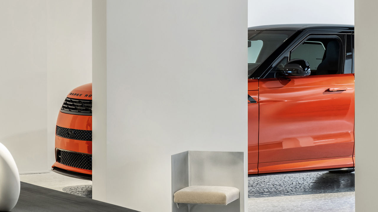 An orange Range Rover with a white pilar in front of it.
