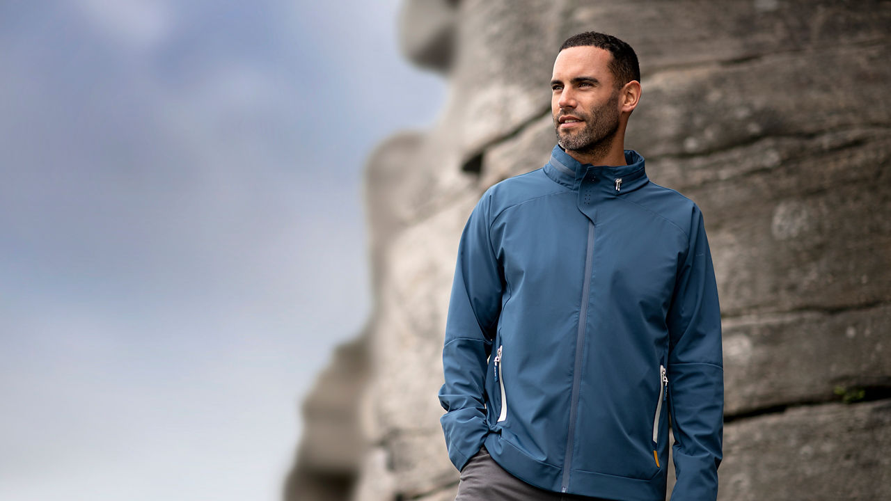 Male model on rocks looking to side wearing softshell jacket