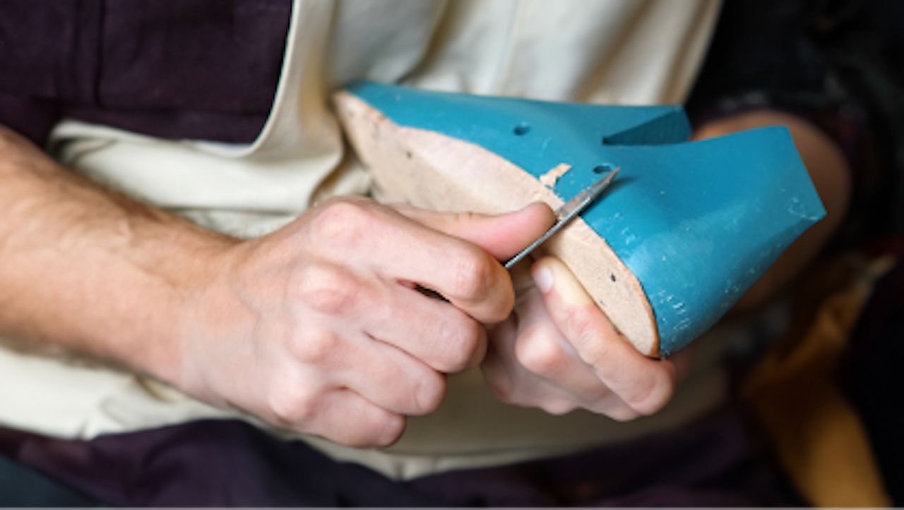 A cobbler working shaping a shoe