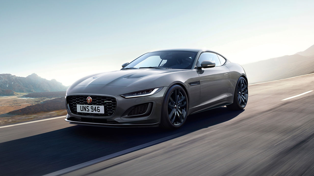 Jaguar F-TYPE running on the road surrounded with mountain at background 