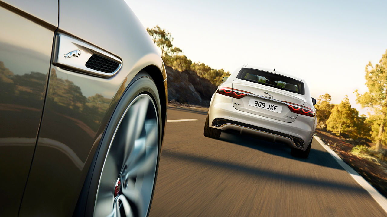 Jaguar XF racing on road surrounded with greenery 