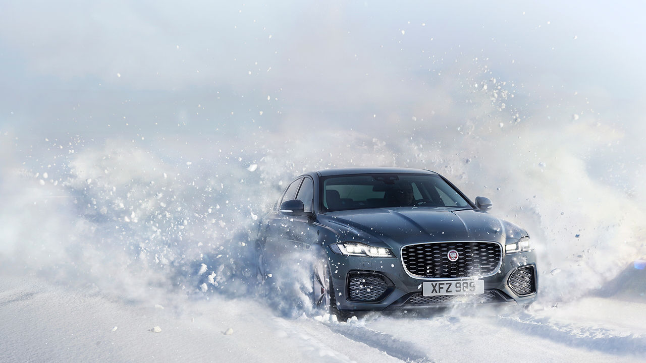 Jaguar XF car passes through a snowdrift and snowy land road at winter