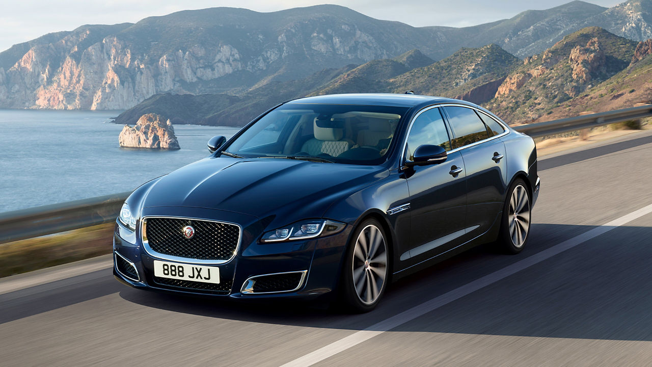 Jaguar XJ running on road surrounded mountains and river