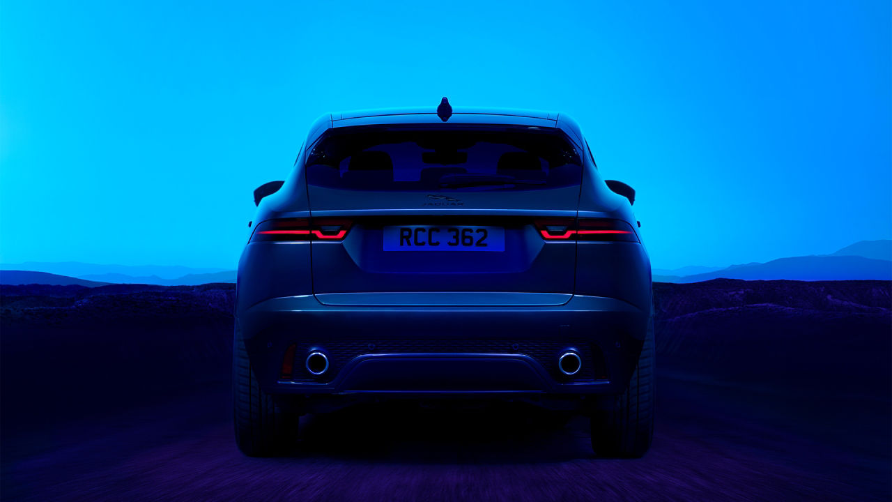 The rear angle of a Jaguar E-PACE as it drives on an open road through a desert landscape