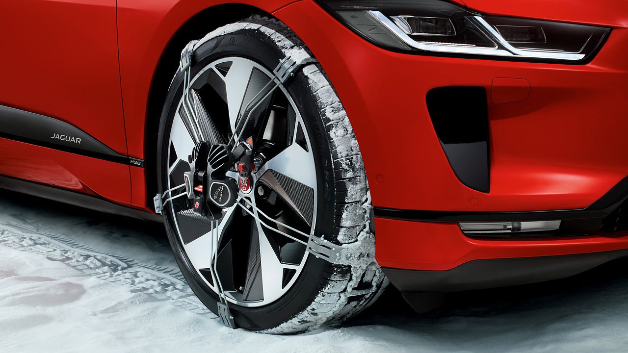 Jaguar I-Pace Car wheel with winter tire and snow chain in snow