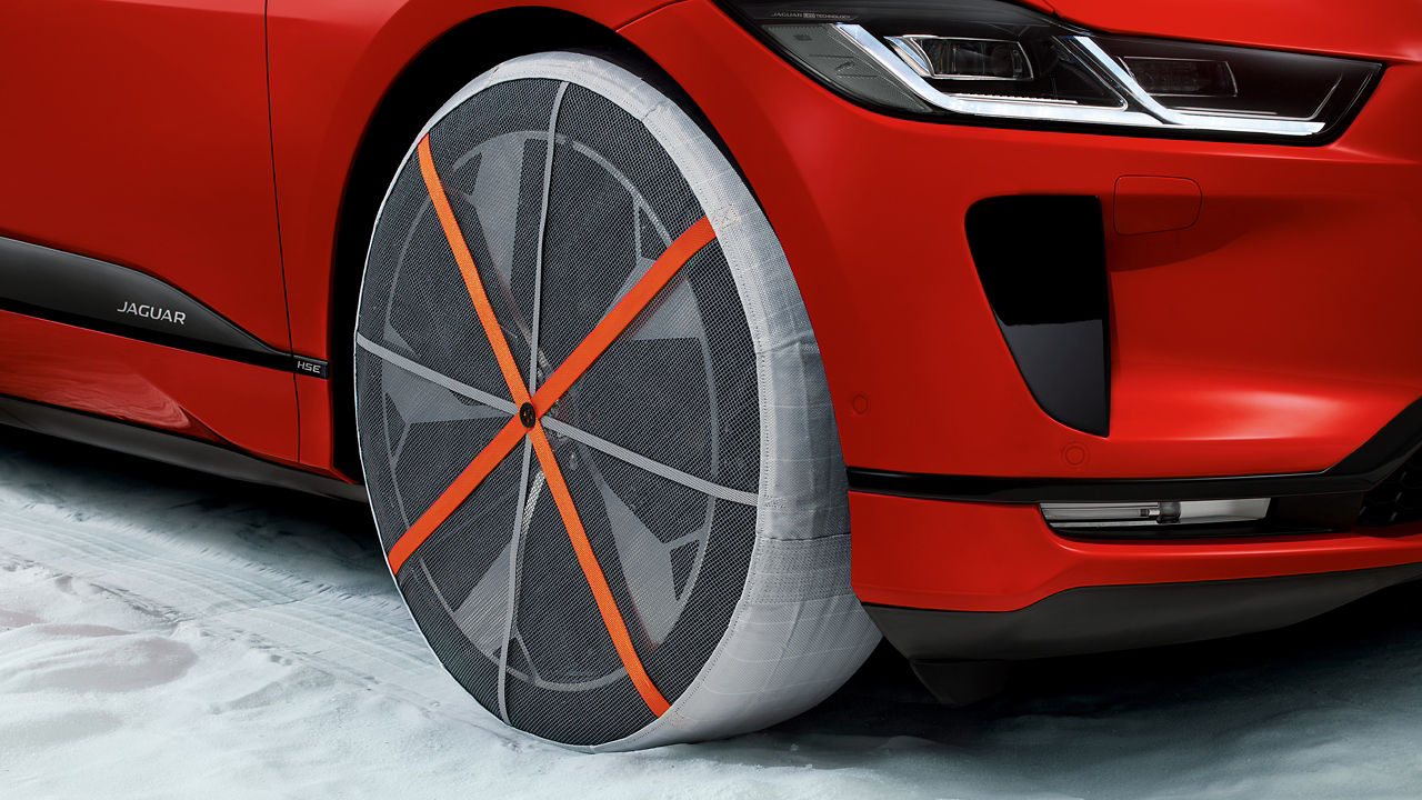 Jaguar I-Pace Car wheel with winter tire and snow chain in snow