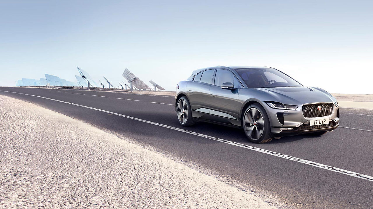 Jaguar I-Pace running on the road and with solar power plant background 