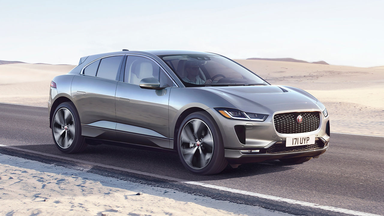 Jaguar I-PACE running on desert road covered with sand