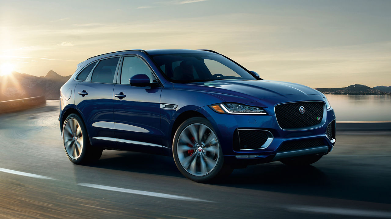 Jaguar F-PACE running on river side road surrounded with mountains