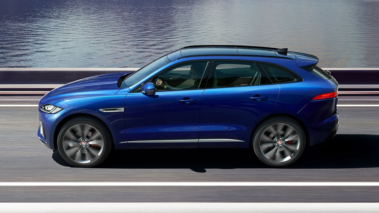 Jaguar F-PACE running on highway surrounded by mountains and river