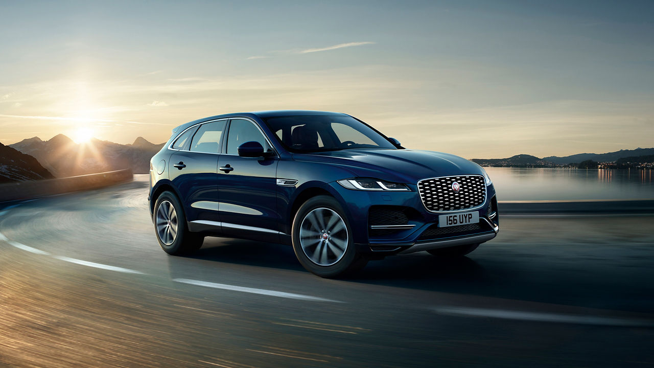 Jaguar F-PACE running on river side road surrounded with mountains