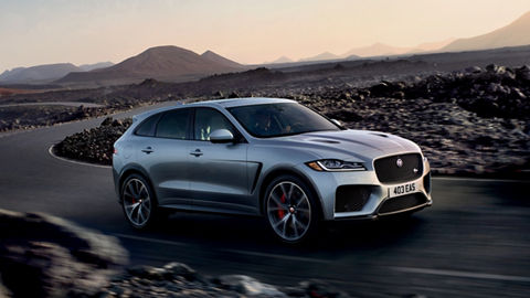 Jaguar XF running on road surrounded with rocks and mountain