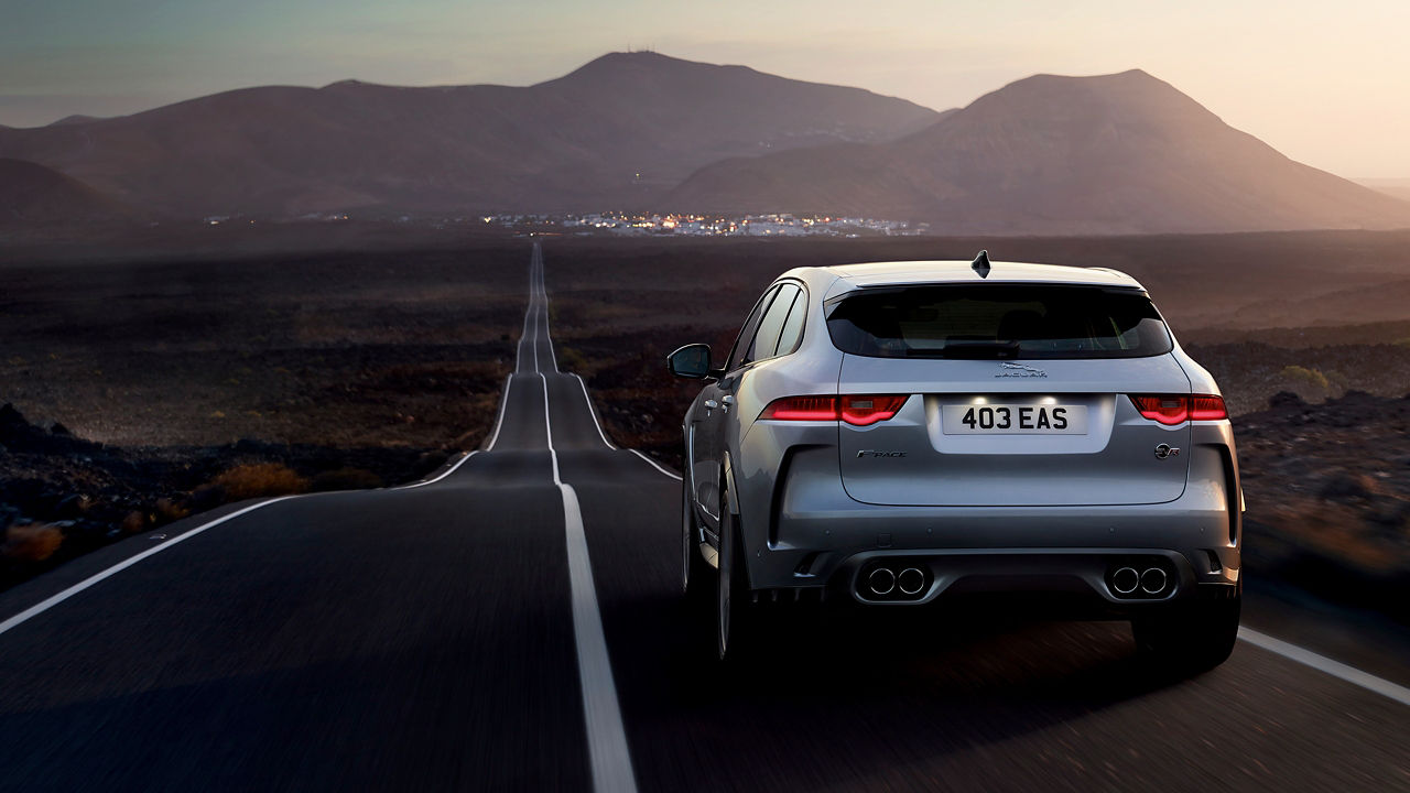 Jaguar F-Pace car moving on asphalt road, Back view