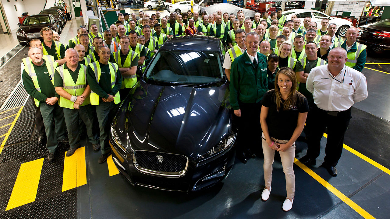 Workshop workers standing beside Jaguar XF 