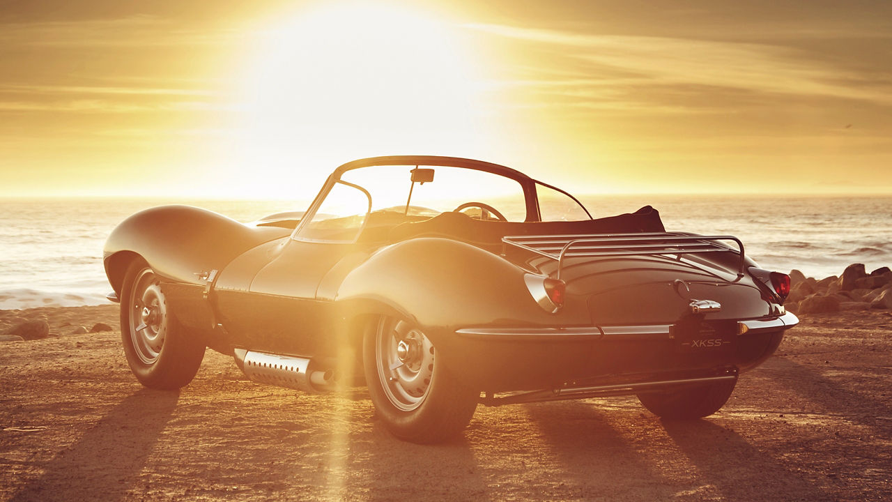 Parked Jaguar XKSS  on the beach with sunset background