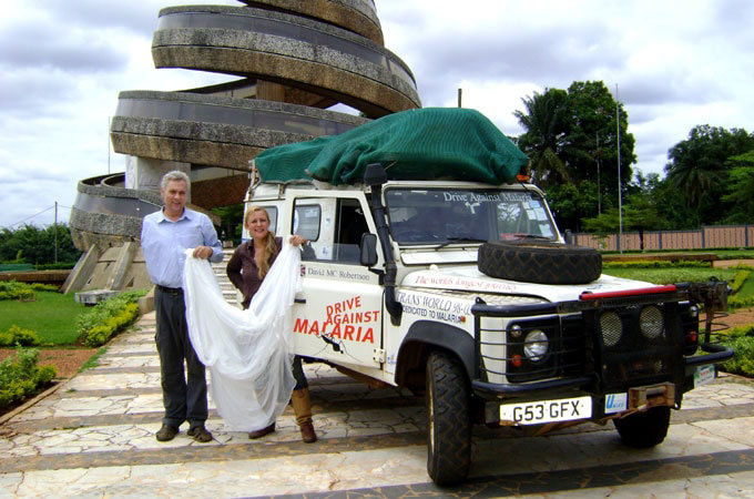 Range Rover with Drive against Malaria sign and 2 people standing outside of it