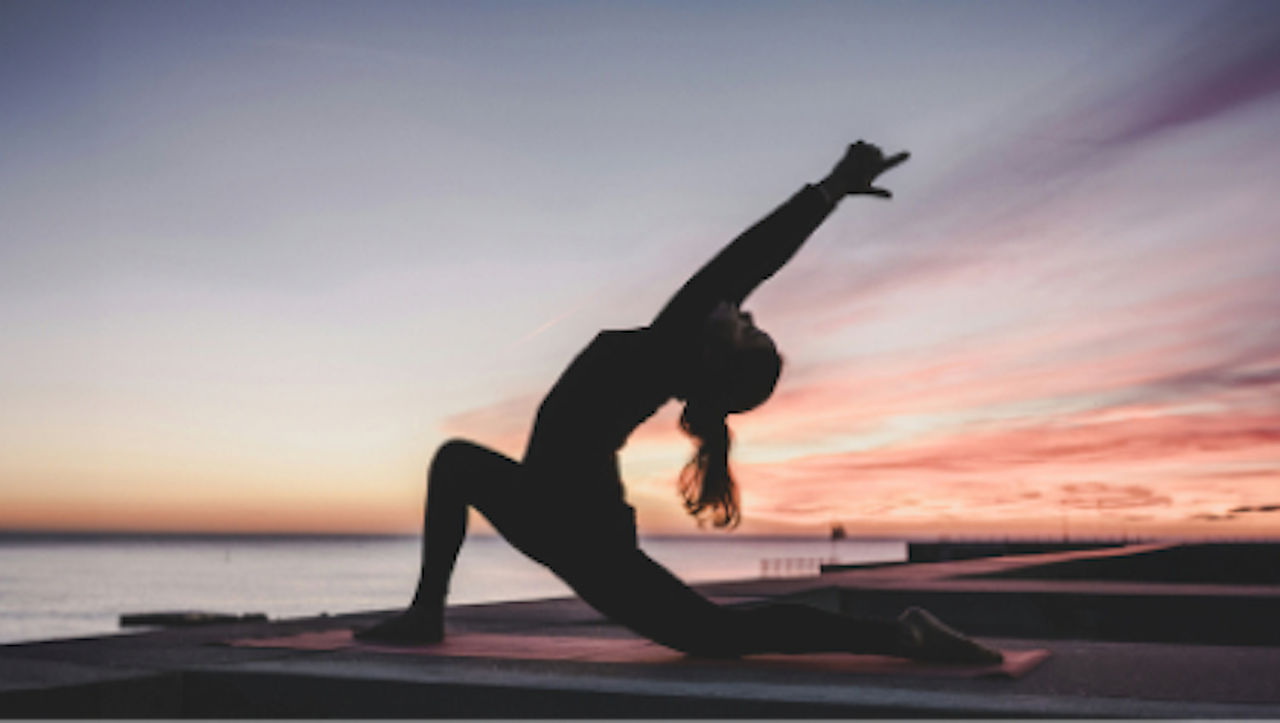 Side view of a woman doing yoga at the sunset.